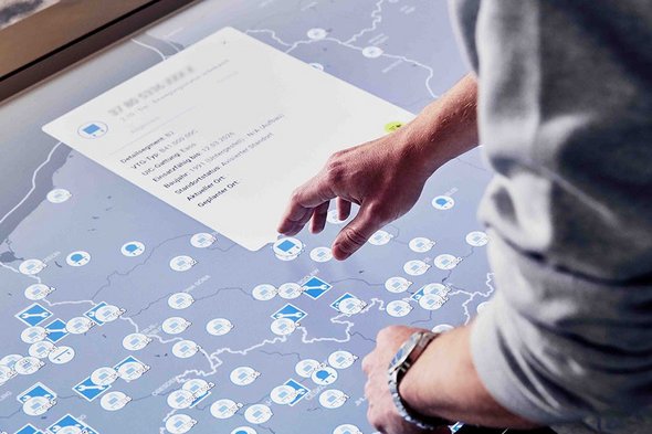 Hand zeigt auf einem Touchdisplay mit Daten